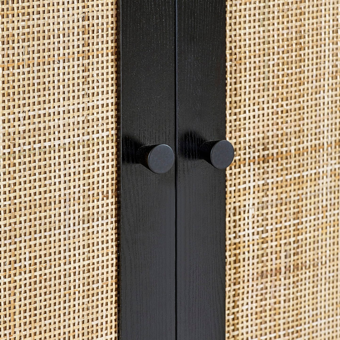 Close-up of the natural cane door weave and black metal hardware on the black oak wardrobe