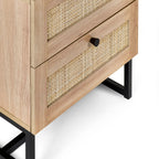 Close-up view of natural cane rattan drawer fronts and black metal legs on oak bedside table