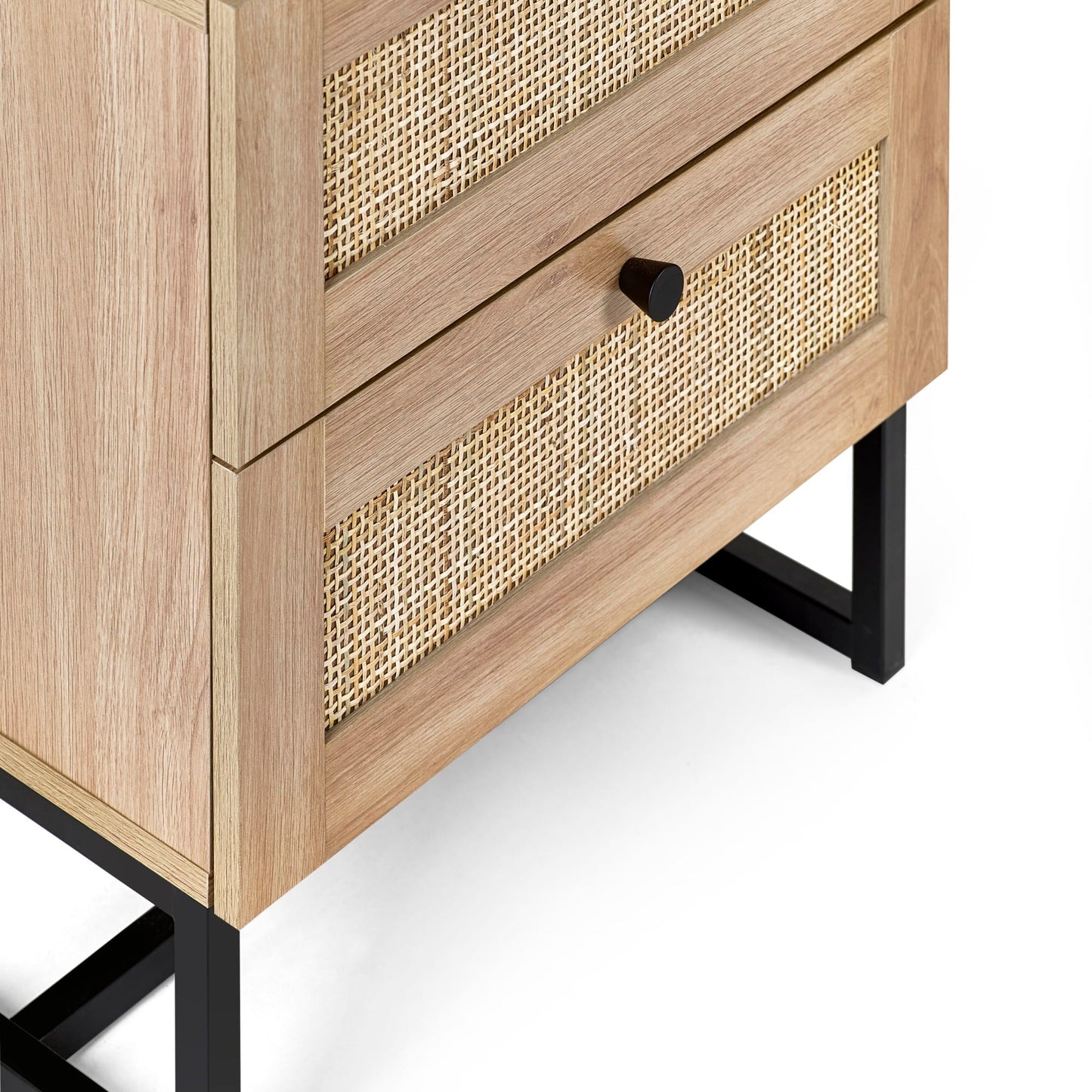 Close-up view of natural cane rattan drawer fronts and black metal legs on oak bedside table