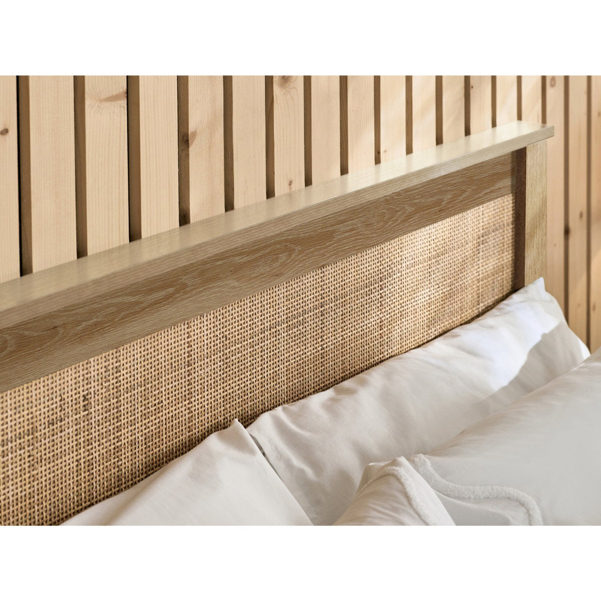 Close-up of the woven rattan cane headboard within the natural oak frame