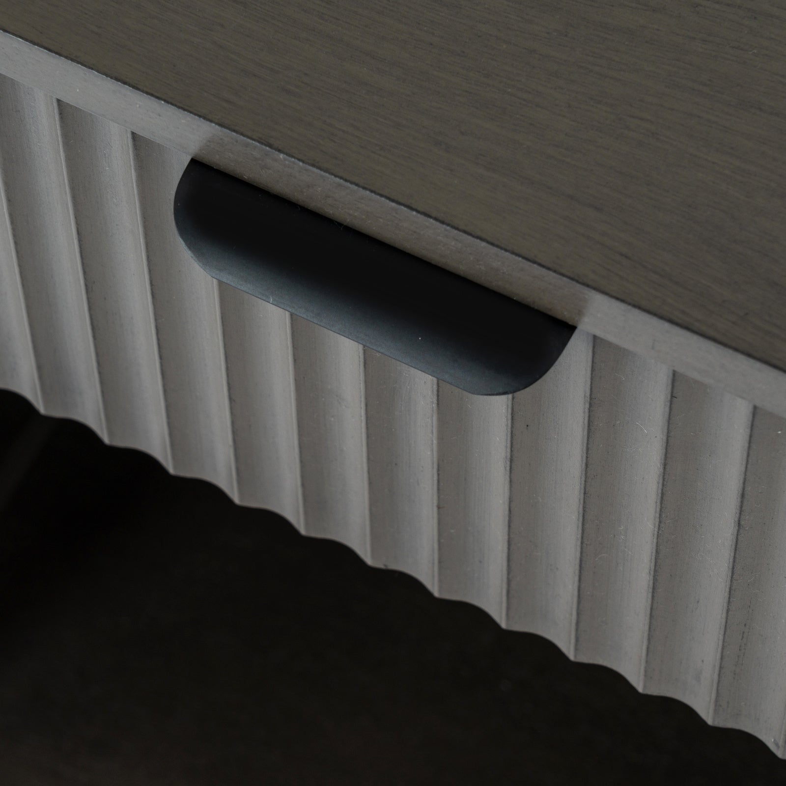 Close-up shot showing the black metal lip handle and vertical fluted wood detail on the top drawer