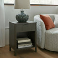 Reed fluted 1 drawer side table styled next to a lounge chair with a table lamp and books in the open cubby