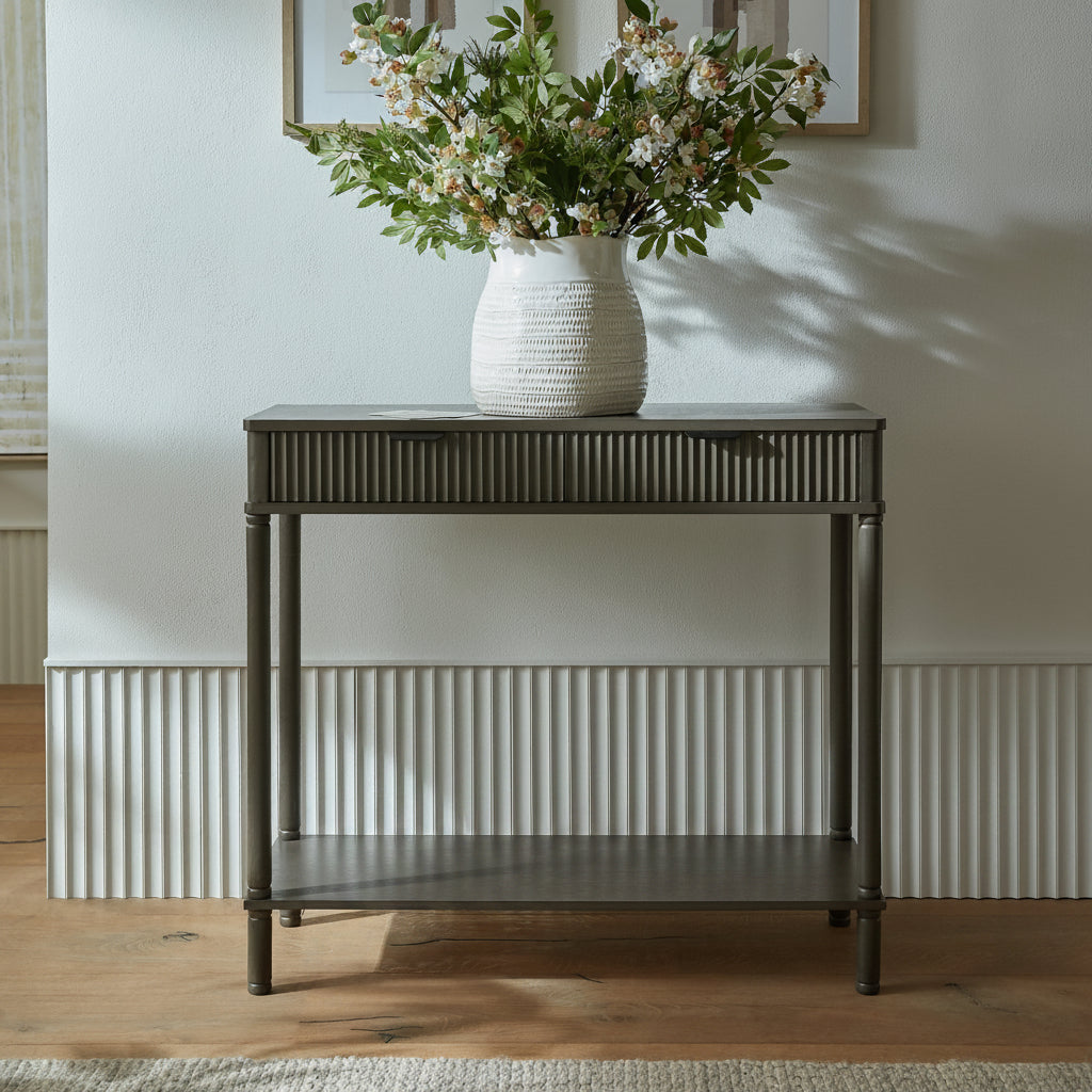 Reed fluted 2 drawer console table styled in a hallway with a floral vase on top and candles on the open lower shelf