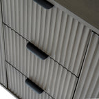 Detail view of the sleek black lip handles and fluted texture on the central drawers of the reed cabinet