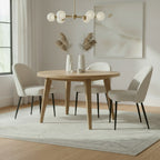 Sorelle boucle dining chairs with black legs arranged around a round wooden dining table on a neutral rug