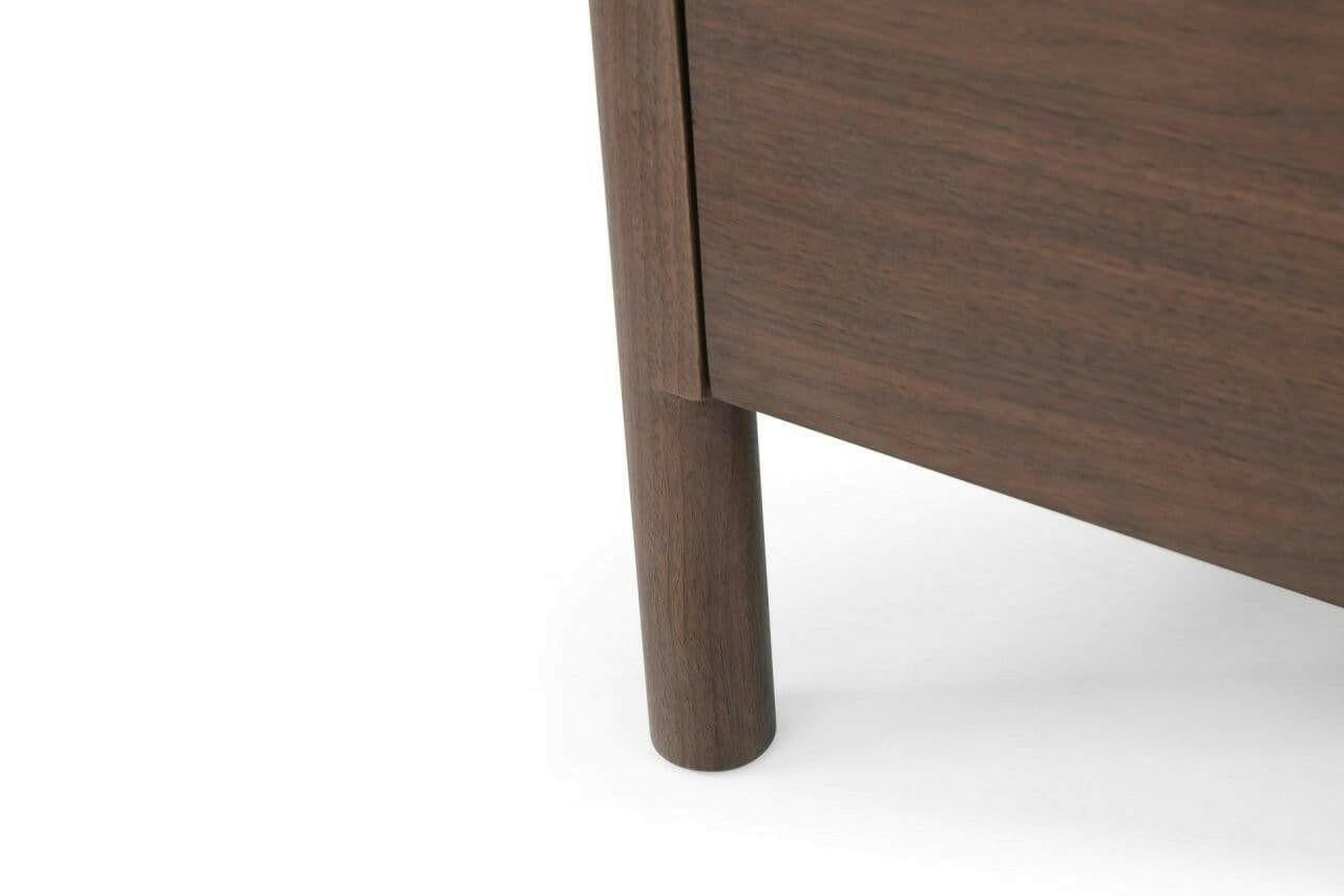 Close-up detail of Willow wooden sideboard  showing a cylindrical leg and part of the drawer front on a white background.
